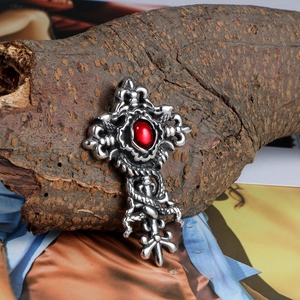 Gothic stainless steel dragon cross pendant with red gemstone on natural wood bark