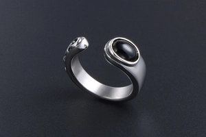 Close-up of vintage steel ring featuring black oval stone and intricate scrollwork detail