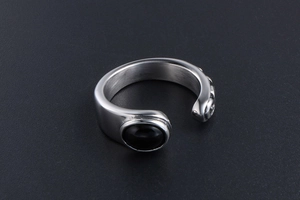 Detail of vintage steel ring featuring black oval stone and textured relief patterns