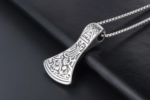 Detailed macro view of vintage silver Viking axe pendant with ornate Nordic carvings