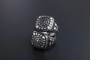 Macro shot of vintage titanium steel ring featuring spiral pebble texture and oxidized finish