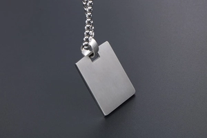 Macro shot of rectangular brushed titanium steel pendant with silver bead chain necklace