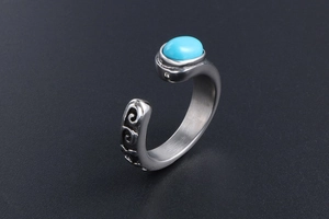Detail of vintage steel ring with oval turquoise stone and engraved floral scroll pattern