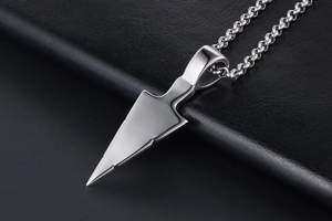 Macro shot of mirror-polished triangular arrow pendant on heavy chain link texture