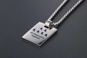 Macro detail of silver titanium pendant with seal cutouts and French engraving