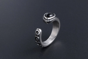 Detail of vintage titanium steel ring with black gemstone and engraved relief patterns