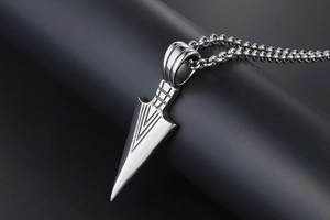 Close-up of polished silver triangular arrow pendant with beaded chain on dark base