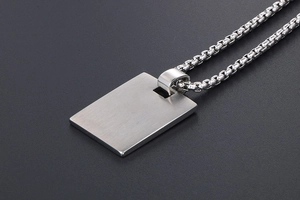 Macro shot of silver brushed metal dog tag pendant with heavy box chain for men