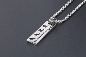 Macro shot of silver pendant engraved with 'Je t'aime pour toujours' on a square bar