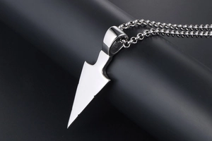 Macro shot of silver arrow pendant with metallic luster on black jewelry stand
