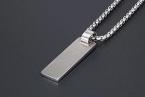 Macro view of silver rectangular tag necklace with brushed metal finish and box chain
