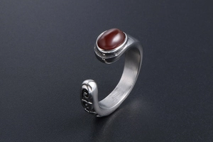 Detail of vintage steel ring with oval red gemstone and intricate scrollwork engraving