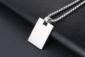 Macro shot of brushed titanium steel rectangle pendant on black textured leather