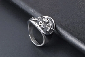 Macro detail of gothic stainless steel ring with five embossed skull heads on wide band