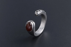 Detail showing the brushed silver finish and inlaid reddish gemstone on retro ring