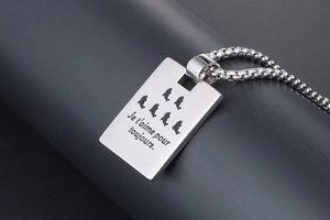 Macro detail of silver rectangular steel pendant with dolphin cutouts and French engraving