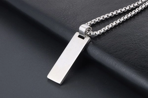 Macro detail of silver minimalist rectangular pendant with brushed finish on box chain