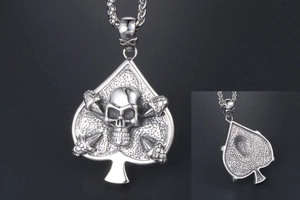 Macro detail of gothic silver spade pendant featuring a central skull and crossbones design