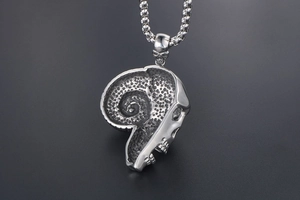 Macro detail of vintage goat skull pendant with oxidized steel texture and box chain