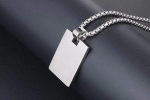 Close-up of brushed titanium rectangle pendant on box chain for men's fashion jewelry