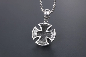 Macro shot of punk iron cross pendant with skull bail and hammered metal texture