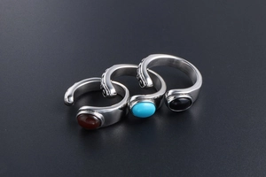 Detail of three vintage titanium steel rings with red, blue, and black gemstones