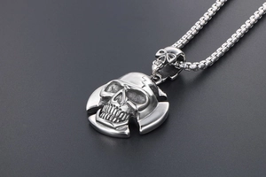 Macro shot of punk skull pendant in aged steel with intricate carvings on box chain