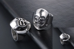 Detailed close-up of punk style stainless steel skull ring on black leather surface