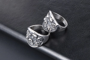 Macro shot of two vintage silver skull rings with punk gothic relief on black leather