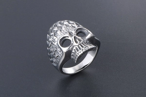 Macro view of detailed silver skull ring showing intricate gothic tooth and bone textures