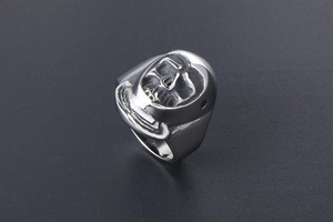 Detailed close-up of a silver skull mask ring with gothic punk design on black surface