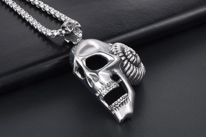 Close-up of vintage steel ram horn skull pendant with textured box chain on black leather