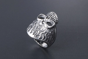 Detail of silver skull ring featuring intricate flame textures and punk metal design