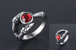 Macro shot of silver bone-shaped bezel holding a faceted red gemstone on a gothic ring