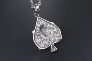 Macro detail of vintage silver heart spade pendant back with textured honeycomb pattern
