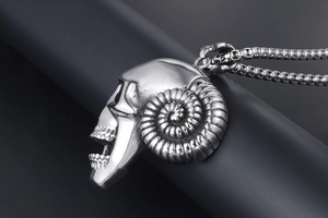 Macro shot of polished steel ram skull pendant with spiral horns and detailed teeth engraving