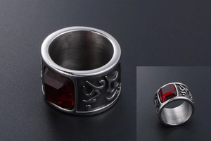 Macro detail of wide stainless steel ring featuring red gemstone and engraved pattern