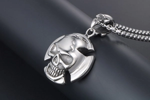 Macro view of polished silver skull pendant with gothic textures and box chain detail
