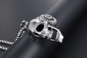 Detailed close-up of a silver gothic skull pendant with curved horns and box chain