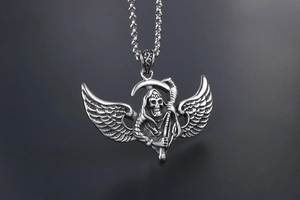 Macro detail of gothic grim reaper pendant with scythe and wings on steel chain
