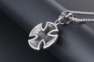 Macro detail of gothic skull bail and iron cross pendant with hammered metal texture