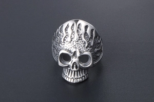 Macro shot of punk style stainless steel skull ring with detailed flame engraving
