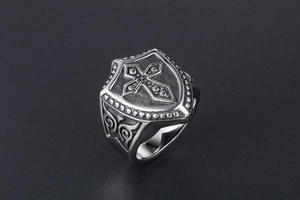 Macro view of vintage shield-shaped ring featuring a cross and ornate floral carvings