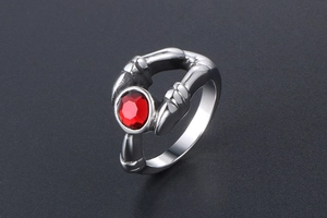 Macro shot of gothic stainless steel ring with red stone held by skeletal hands