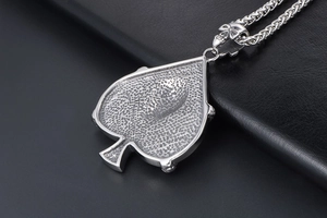 Macro detail of vintage spade pendant showing textured back and skull clasp connector