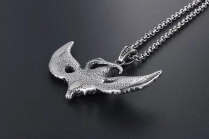Macro detail of silver eagle pendant with intricate texture and classic rolo chain link