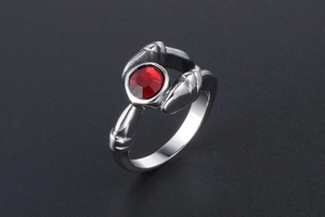 Detail of gothic stainless steel ring featuring a red crystal and claw setting design