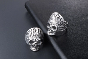 Close-up of gothic skull rings with flame relief detail in polished stainless steel