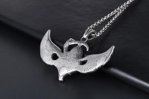 Macro view of flying reaper skull pendant with textured wings and punk steel chain