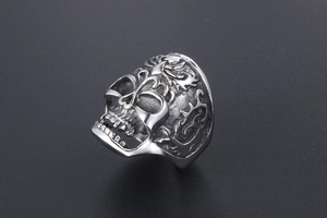 Close-up of vintage stainless steel skull ring featuring intricate gothic flame carvings